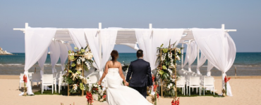 A couple walking across a beach in Puglia to their beach wedding ceremony.