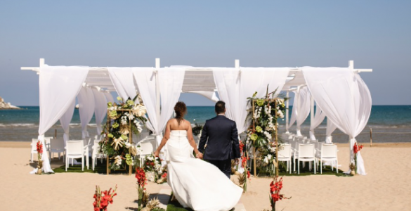 A couple walking across a beach in Puglia to their beach wedding ceremony.