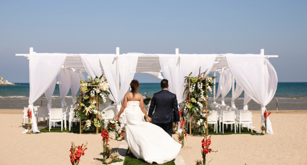 A couple walking across a beach in Puglia to their beach wedding ceremony.